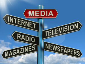 This is an image of a sign post with various types of Media pointing in different directions